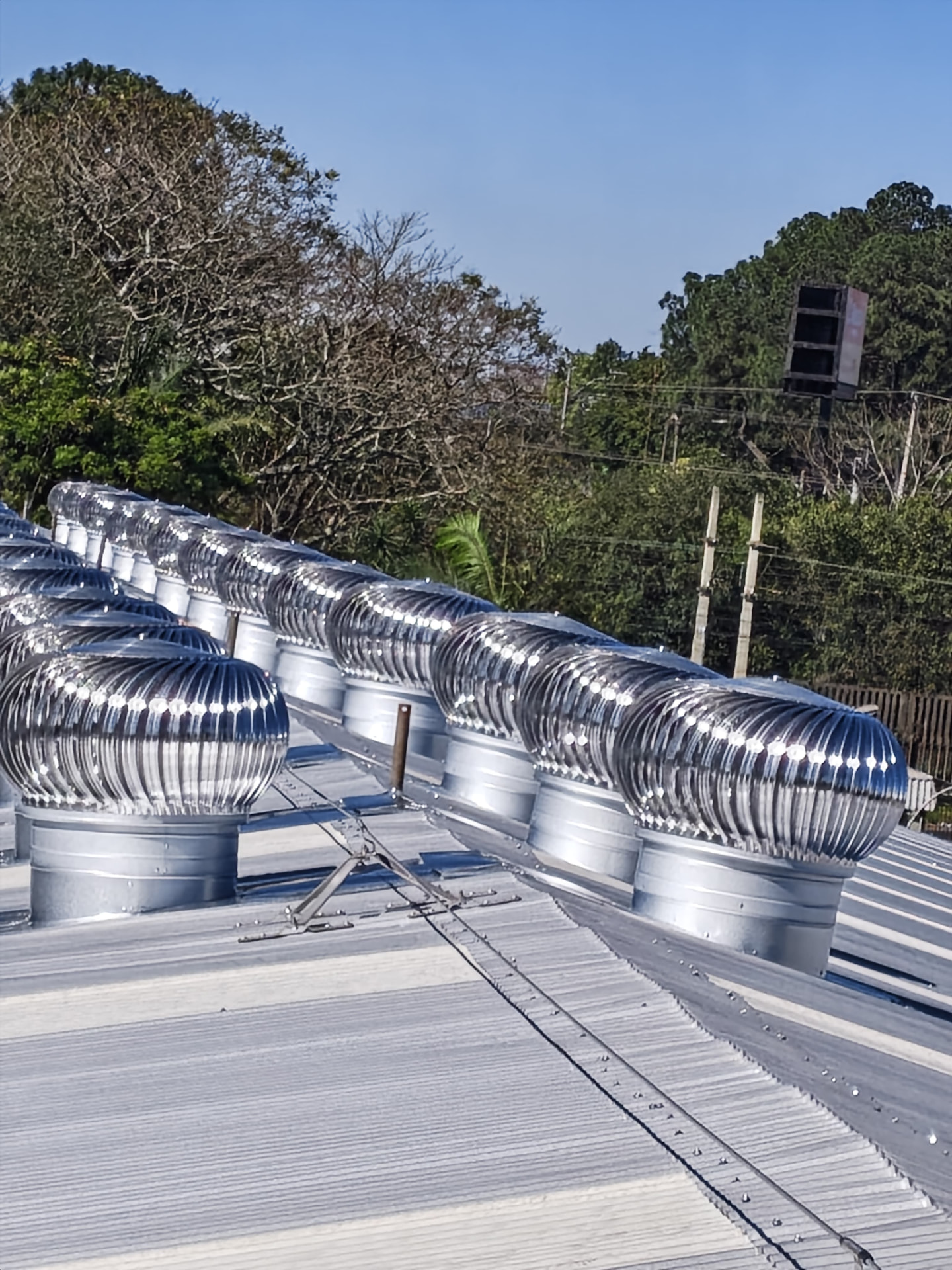 Linha de exaustores eólicos instalados em galpão industrial